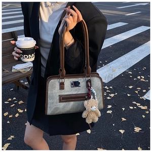 Détail d'un sac cabas rétro avec finitions en cuir, breloque ourson et décor urbain automnal
