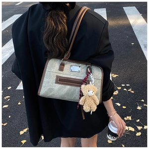Détail du sac cabas vintage vert olive avec breloque ours dans un décor d'automne