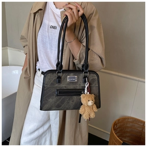 Détail du sac à bandoulière rétro gris foncé avec coutures et breloque ours