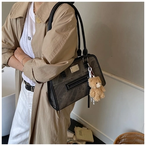 Deep grey tote bag with washed texture and bear charm shown in a commuting outfit