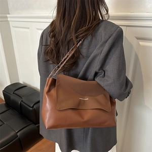 Vintage brown leather tote bag with chain strap shown against a minimalist wall