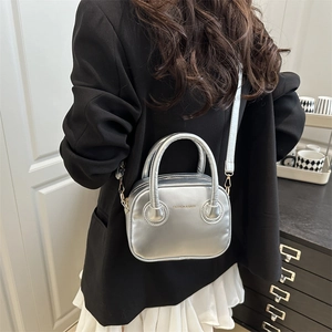 Minimalist silver metallic handbag with circular handles and detachable shoulder strap