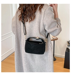 Close-up of black matte leather pillow bag with gold hardware and adjustable strap