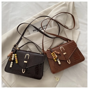Detail of crocodile pattern small square bags with colorful wooden bead charm and gold U-buckle