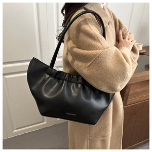 Detail of black pleated soft leather tote bag with gold lettering shown on model
