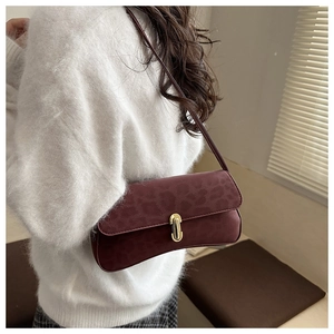 Détail du sac bandoulière bordeaux à motif léopard avec boucle dorée porté par un mannequin