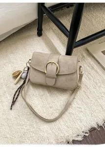 Detail of beige faux suede shoulder bag with gold buckle and baseball charms