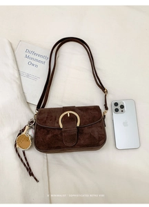 Deep brown suede shoulder bag with gold horseshoe buckle and baseball charm detail