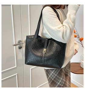 Detailed side view of a black woven texture tote bag with golden metal buckle on a model