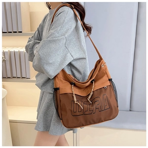 Close-up of brown canvas crossbody bag featuring WIRA print and mesh pocket detail