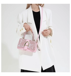 Sac à bandoulière rose en patchwork avec boucle dorée sur un blazer blanc