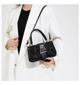 Close-up of stylish black crossbody bag featuring gold buckle and embossed texture