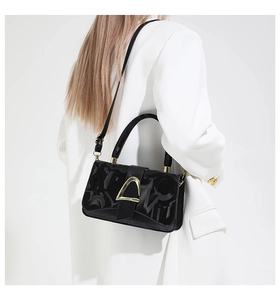 Détail du sac bandoulière en cuir noir avec boucle dorée et motifs gaufrés élégants