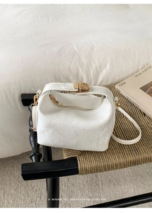 Close-up of white corduroy textured crossbody bag on a woven chair with a retro vibe
