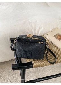 Close-up of black corduroy small square bag with premium gold hardware and clasp