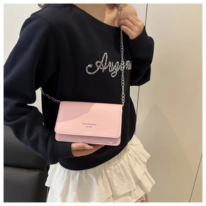 Detail of pink patent leather crossbody bag with silver chain strap and logo lettering