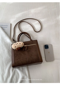 Détail du sac cabas marron en daim avec finitions en cuir et breloque agneau mignon