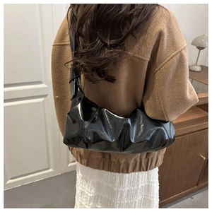Détail du sac plissé noir brillant montrant le cuir souple et la bandoulière élégante