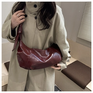 Détail du sac croissant rouge foncé avec anse à gros nœud et finition vernie chic
