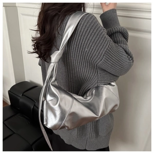 Sac à bandoulière argenté métallisé avec détail de nœud sur la sangle porté par un mannequin
