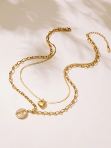 Détail d'un collier double épaisseur en acier plaqué or 18k avec pendentifs cœur et zircon