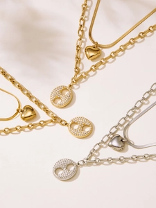 Détail de colliers superposés or et argent avec pendentifs groin de porc et cœur
