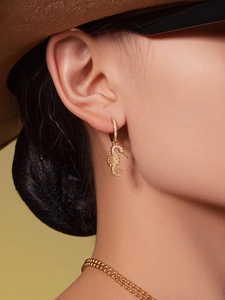 Close-up of a golden seahorse earring featuring detailed micro-paved white zircons