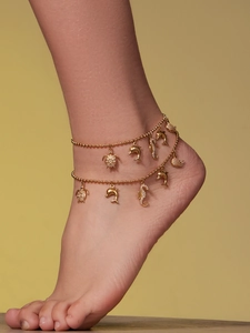 Detail of double-layer gold anklet featuring sea turtle and seahorse charms with crystals