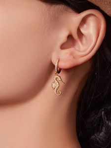 Close-up of a gold-plated seahorse earring with micro-pave white cubic zirconia stones