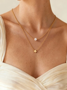 Primer plano de collar de doble capa dorada con colgante de estrella y perla blanca