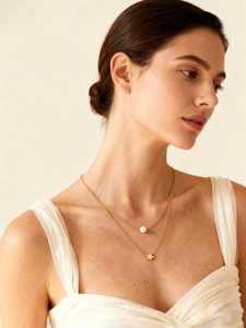 Primer plano de collar doble dorado con perla y estrella sobre una modelo