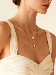 Detalle de collar de doble capa dorado con perla blanca y colgante de estrella en modelo