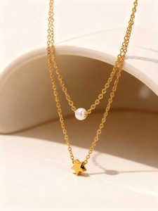 Detalle de un collar de doble capa dorado con una perla blanca y un colgante de estrella