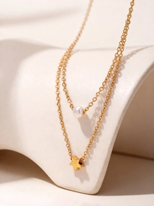 Detalle del collar de doble capa dorado con una perla blanca y un colgante de estrella