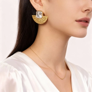 Gros plan détaillé de boucles d'oreilles dorées en forme d'éventail avec reliefs de plumes
