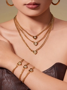 Detail der mehrlagigen Goldketten und Armbänder mit Herzanhängern und Zirkon-Initialen