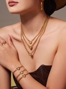 Detailaufnahme mehrlagiger 18k Gold-Herzketten und Armbänder mit Zirkonia-Buchstaben