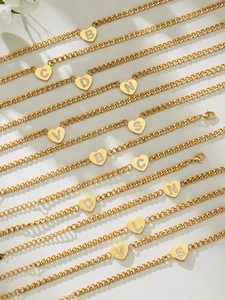 Makroaufnahme von 18k vergoldetem Panzerarmband mit Zirkonia-Herz-Buchstabenanhänger