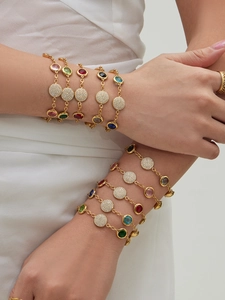 Detailed view of layered gold chain bracelets with colorful round gemstones and zircon discs