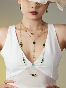 Elegante conjunto de collar dorado con piedras de cristal verde esmeralda y pendientes