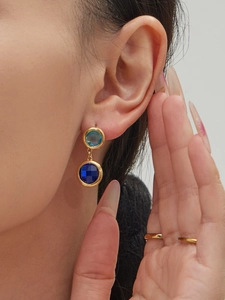 Close-up of model wearing two-tier round blue crystal drop earrings in gold finish