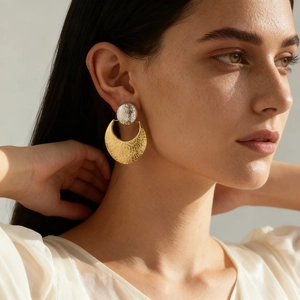 Two-tone hammered metal earrings in gold and silver finish on female model