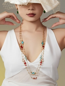 Detalle del collar dorado multicapa con piedras de colores y pendientes a juego