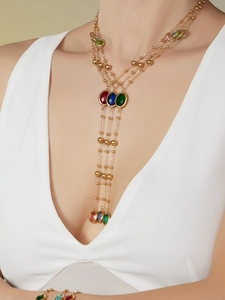 Detalle de collar largo dorado con piedras de cristal de colores y borlas largas