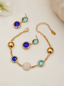 Detail of 18k gold plated jewelry set with blue gemstones and sparkling zircon pavé charms