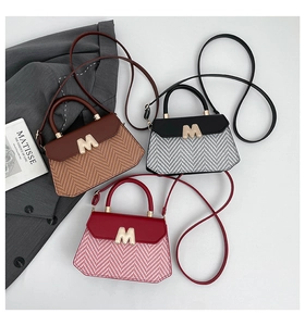 Detailopname van geweven patchwork handtassen met metalen M-gesp in drie verschillende kleuren