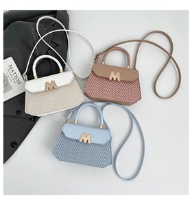 Detailoverzicht van geweven crossbodytassen in wit blauw en roze met metalen M sluiting