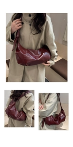 Détail du sac demi-lune rouge foncé brillant avec texture plissée et large bandoulière