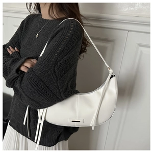 Detail of white leather hobo bag with vertical stitching and elegant metal buckle