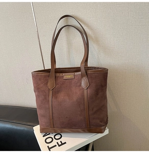 Detail of a brown suede tote bag with leather trim and professional fashion logo